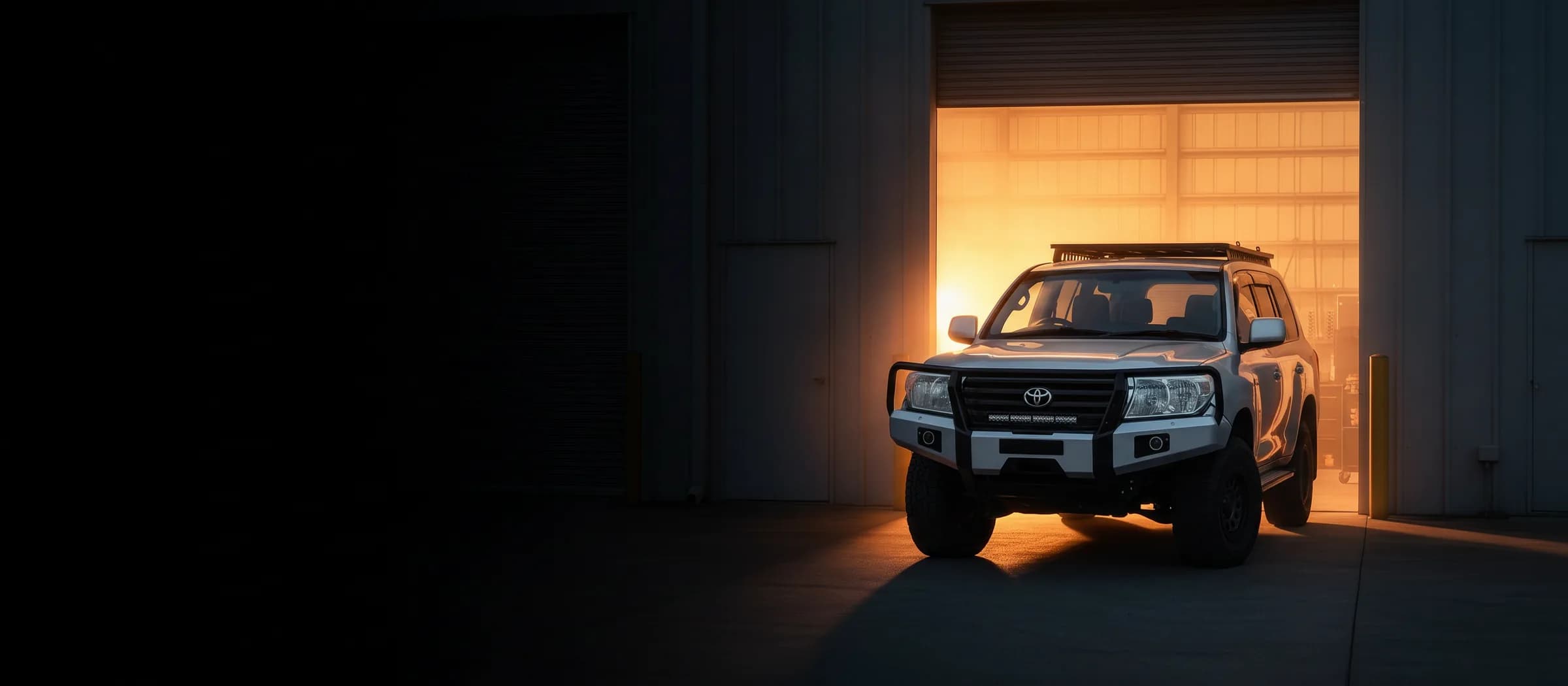 A LandCruiser 200 parked in front of the Narangba workshop at golden hour