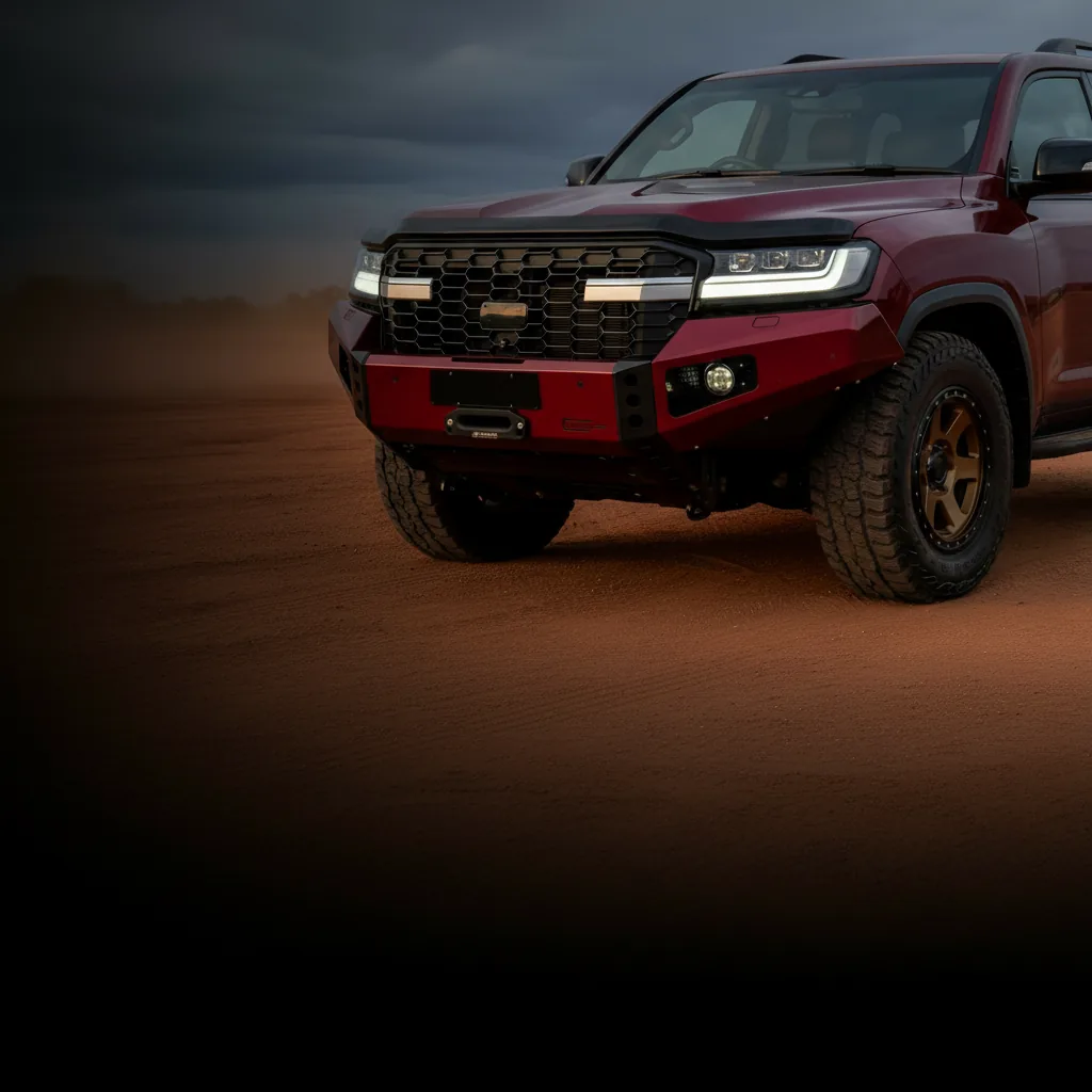 A red LandCruiser 300 Series with a Raslarr bull bar on a red-dirt track at dusk